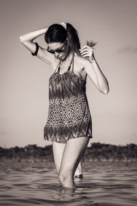 Woman standing at beach against sky