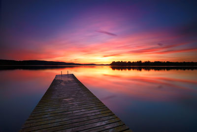 Pier over lake against sky during sunset