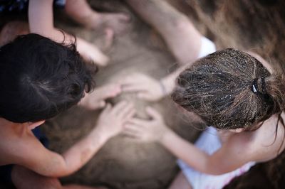 Directly above shot of friends playing with sand at beach