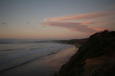 Scenic view of beach against sky at sunset