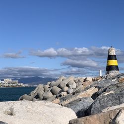 Lighthouse by sea against sky