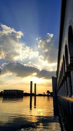 Silhouette of wooden post in canal against sky