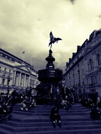 Statue in town square against cloudy sky