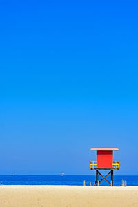 Lifeguard hut on beach against blue sky