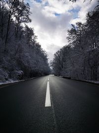 Empty road along bare trees