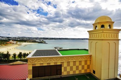 Building by sea against cloudy sky