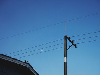 Low angle view of electricity pylon against blue sky