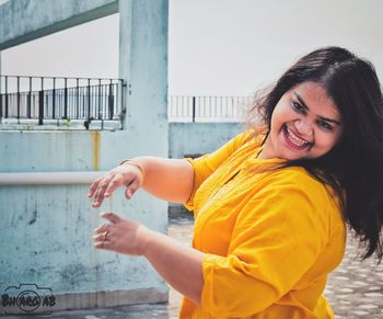 Portrait of smiling woman against railing