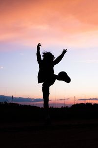 Silhouette of kid jumping on field against sky during sunset