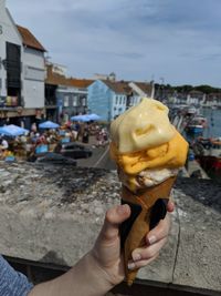 Hand holding ice cream cone in city