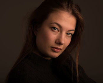 Close-up portrait of a beautiful young woman over black background