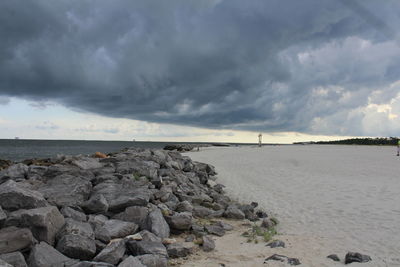 Scenic view of beach and sea against storm clouds