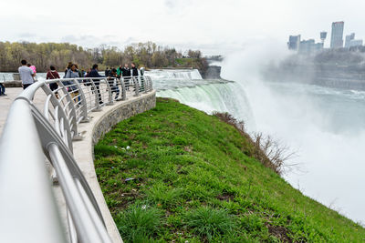 People on riverbank against sky