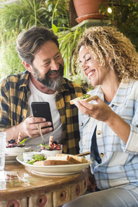 Portrait of friends using mobile phone while sitting on table