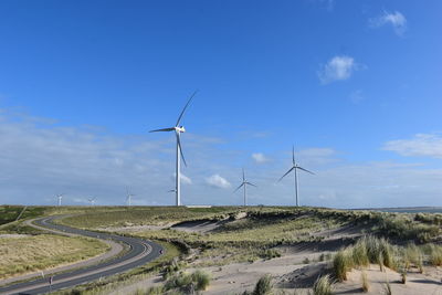 Wind turbines on field against sky