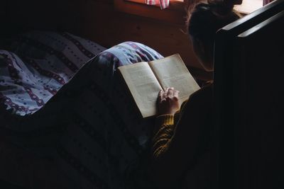 Woman reading book on bed in wooden cottage