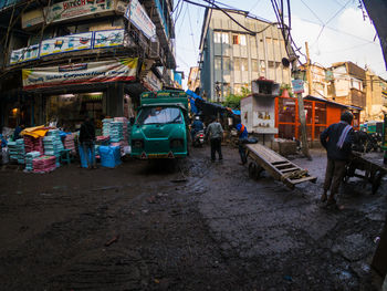 People on road by buildings in city