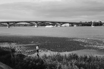 Rear view of man on bridge over river against sky