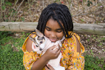 High angle view of smiling girl carrying cute chihuahua while standing in park