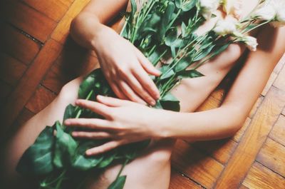 Midsection of naked woman covering herself with plants