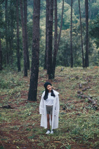 Full length of woman standing at forest