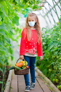 Full length of girl holding vegetables in basket