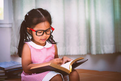 Girl holding book on couch at home