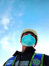 Low angle view of man standing against blue sky