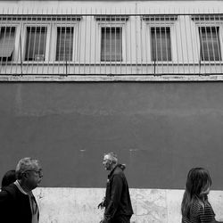 Rear view of people standing against building