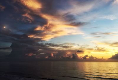 Scenic view of sea against cloudy sky at sunset