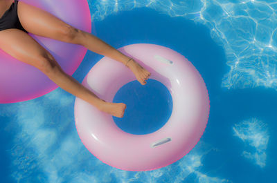 Lows section of woman relaxing on inflatable ring in swimming pool