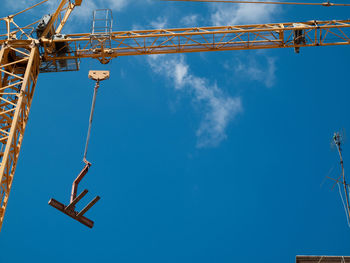 Low angle view of crane against clear blue sky