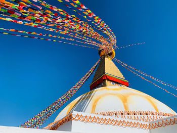 Low angle view of ferris wheel against clear blue sky