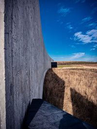 Stone wall on field against blue sky