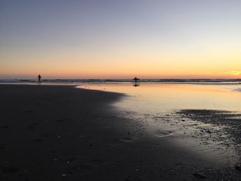 Scenic view of beach against clear sky during sunset