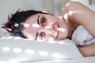 Portrait of woman lying down on bed