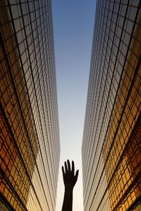 Low angle view of person hand against sky