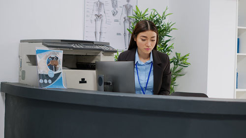 Portrait of young woman using mobile phone in office