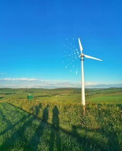 Windmill on field against blue sky