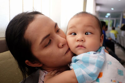 Close-up of baby boy with mother suffering from cross-eyed at hospital