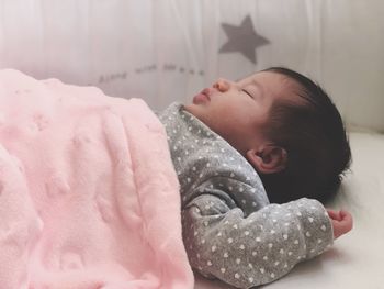 Close-up of baby girl sleeping on bed at home