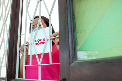 Woman holding umbrella standing by window