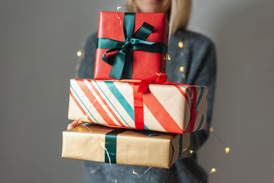 Unrecognizable woman holds a stack of beautifully wrapped christmas presents.