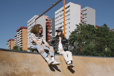 Smiling young man talking with girlfriend sitting on sports ramp