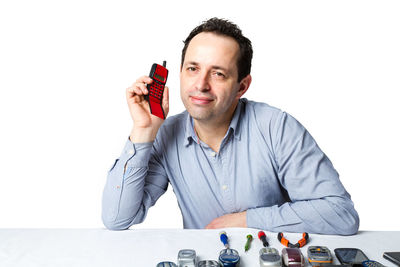 Portrait of man sitting on table against white background