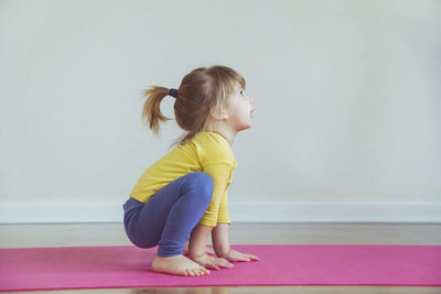 Charming baby doing yoga at home. place for text