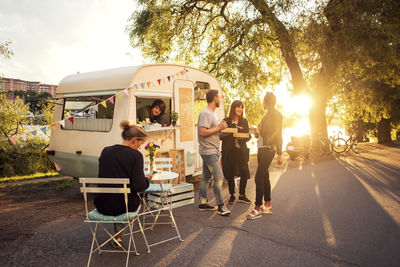 Owner looking at customers standing on street through food truck window