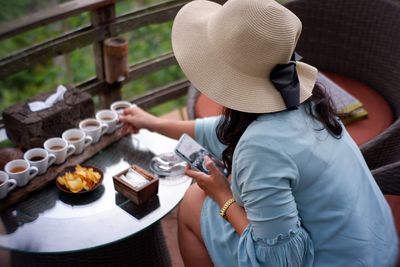 Woman holding drink in cup while sitting at table