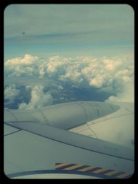 Cropped image of airplane wing over clouds