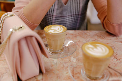 Midsection of woman with coffee cup on table